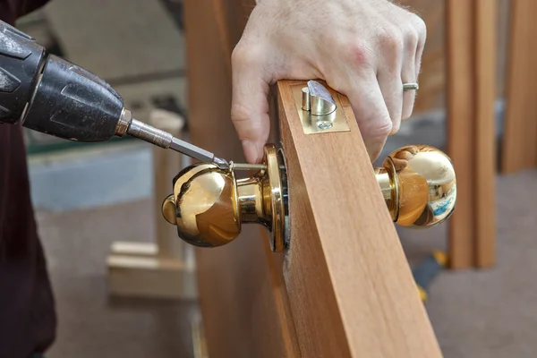Installation door knob with lock, woodworker screwed screw, using screwdriver.